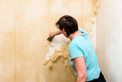 process-removing-old-wallpaper-cleaning-wall-from-wet-old-wallpaper-with-metal-spatula-min